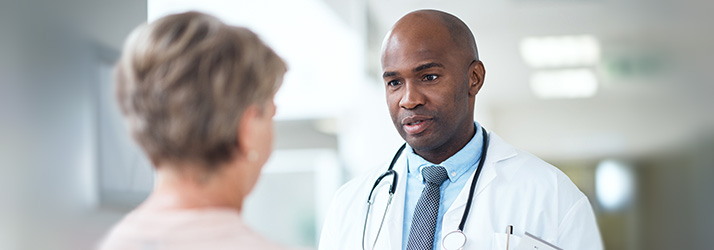 Male doctor in white coat talking with a patient during a consultation for finding a chiropractor in Medway area.