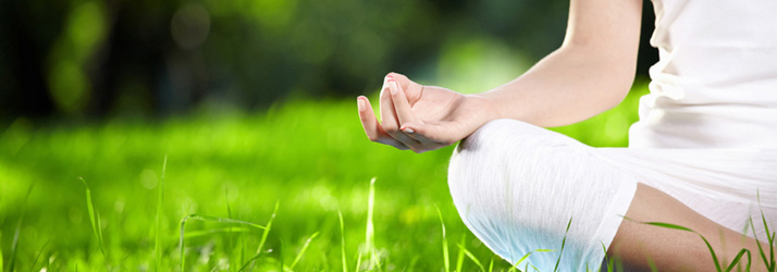 Person practicing meditation on lush green grass, illustrating routine chiropractic wellness care guidance offered by a dedicated Medway chiropractor.