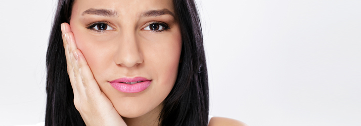 Woman touching her aching jaw in discomfort, illustrating how gentler treatments from a Medway chiropractor may help relieve TMJ pain.